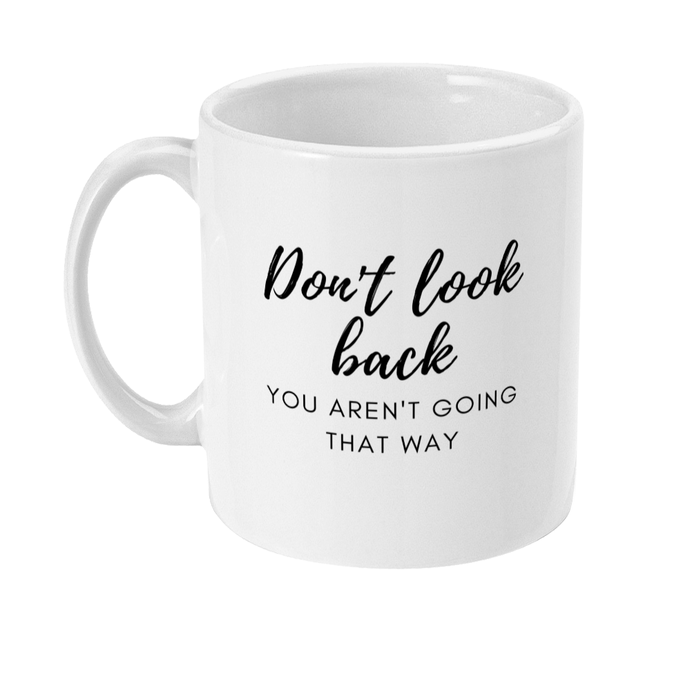 Mug with text in a script style font that is large and says Don't look back. Smaller text underneath in a sans serif style font in caps that says you aren't going that way. Full text reads: Don't look back, you aren't going that way