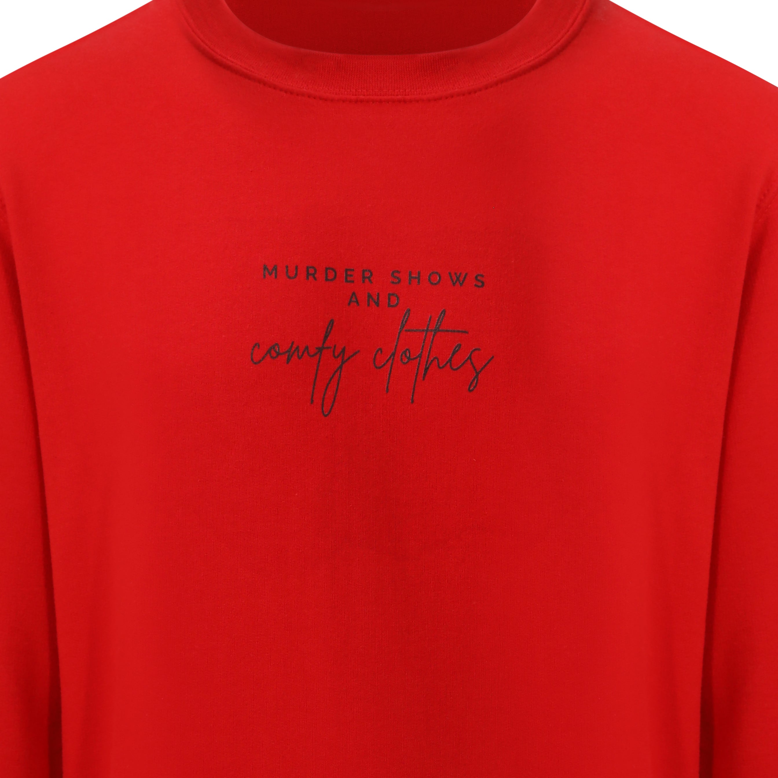 Sweatshirt that says: Murder shows and comfy clothes. Murder shows is in caps and sans serif style font, comfy clothes is in a handwritten style font. Text is small and placed in the centre of the chest, stretching as far as the neckline