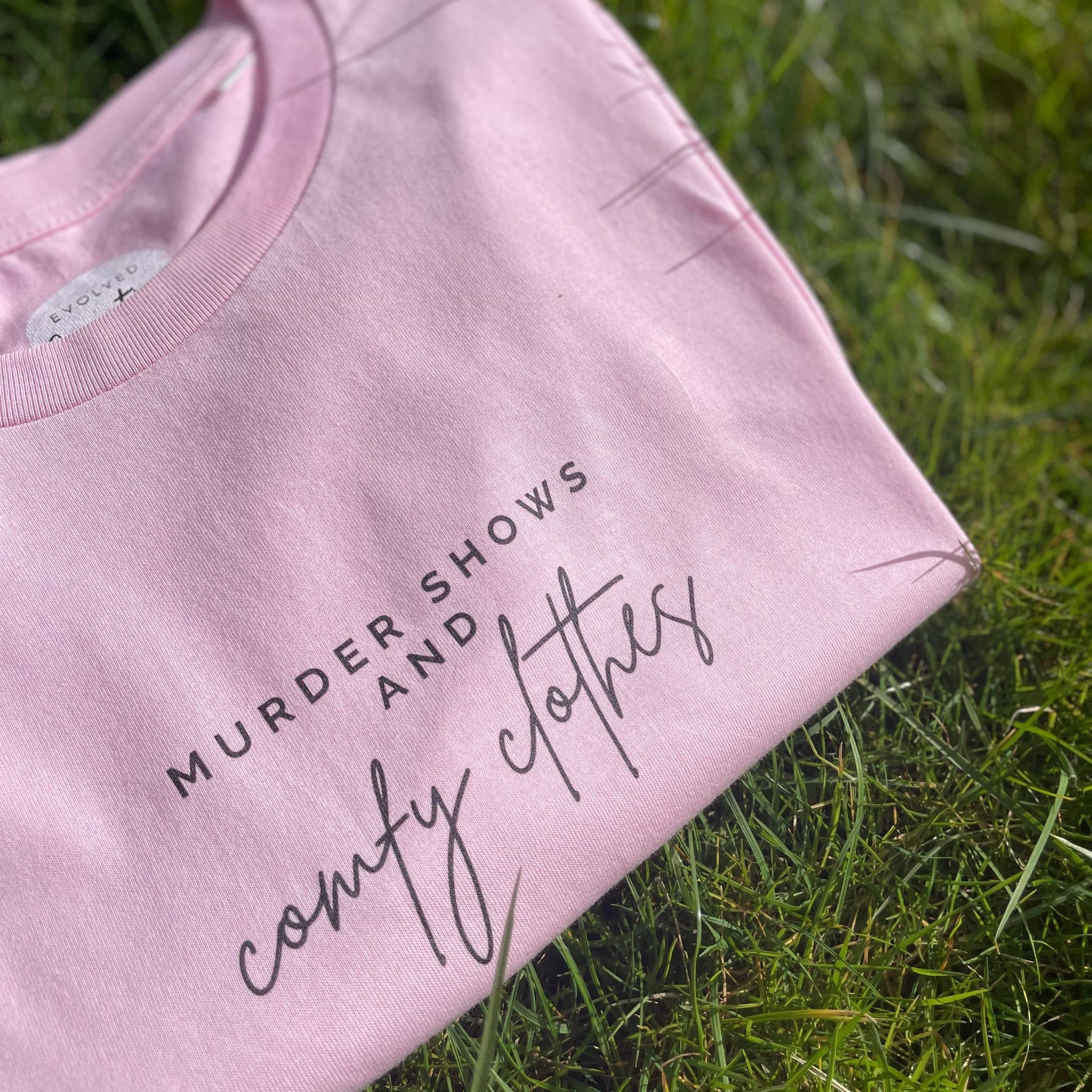 Organic T-Shirt that says: Murder shows and comfy clothes. Murder shows is in all caps in a serif font, and comfy clothes is in a handwriting style font