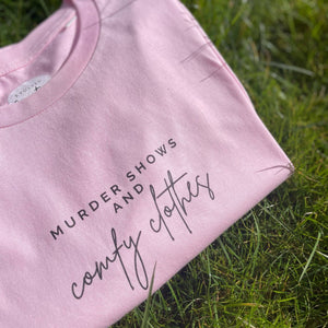 Organic T-Shirt that says: Murder shows and comfy clothes. Murder shows is in all caps in a serif font, and comfy clothes is in a handwriting style font