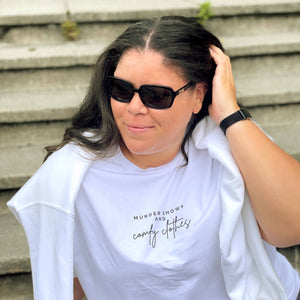 White Organic T-Shirt that says: Murder shows and comfy clothes. Murder shows is in all caps in a serif font, and comfy clothes is in a handwriting style font 