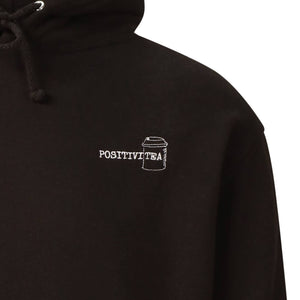 Jet Black hoodie that reads positivitea on the left hand side of the hoodie in a logo sized style. The tea section of the word has a takeaway style cup around it to give a spin on the positivitea word