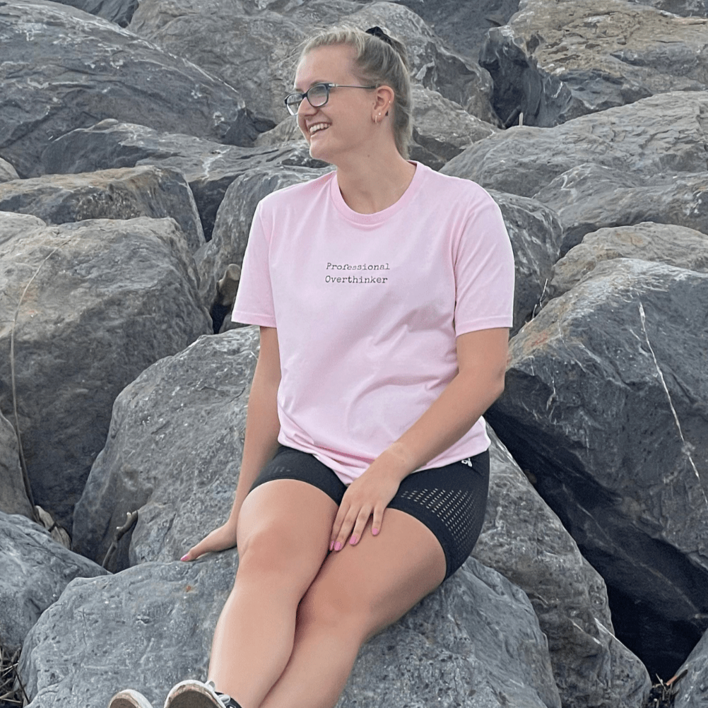 Cotton Pink Organic T-Shirt that reads professional overthinker in a typewriter style font. Professional Thinker takes up the middle section of the chest and is a small style size to not take up to much of the t-shirt