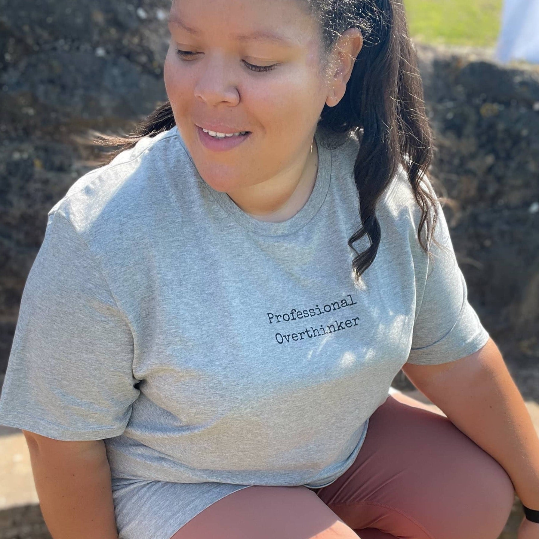 Heather Grey Organic T-Shirt that reads professional overthinker in a typewriter style font. Professional Thinker takes up the middle section of the chest and is a small style size to not take up to much of the t-shirt