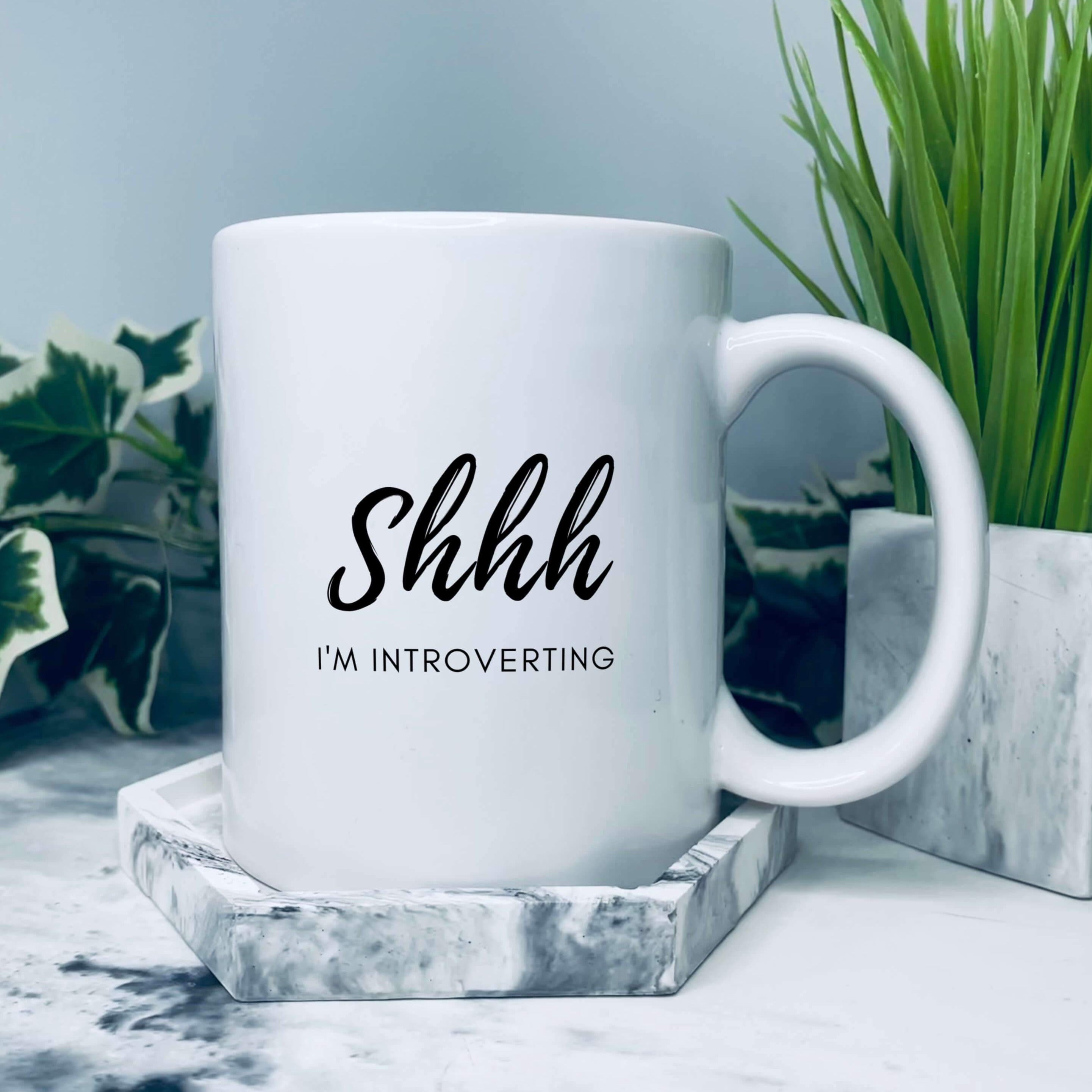 Mug that says: Shhh I'm introverting. Shhh is in large script text, and I'm introverting is in small sans serif text underneath